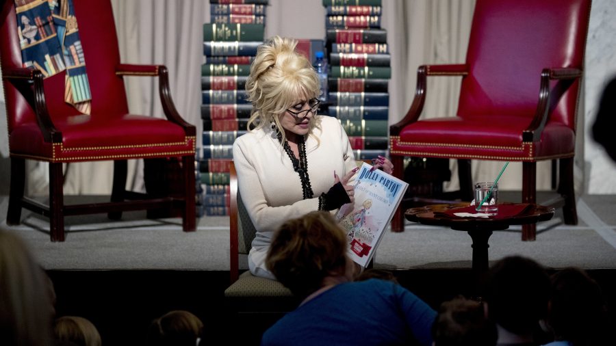 Singer-songwriter Dolly Parton reads her book "Coat of Many Colors" to children during an an event where her organization Imagination Library donates it as the 100 millionth book to the Library of Congress collection, Tuesday, Feb. 27, 2018 in Washington. The Library of Congress and Imagination Library also announce a story time for children on the last Friday of each month in the Great Hall of the Thomas Jefferson Building from March through August. (AP Photo/Andrew Harnik)