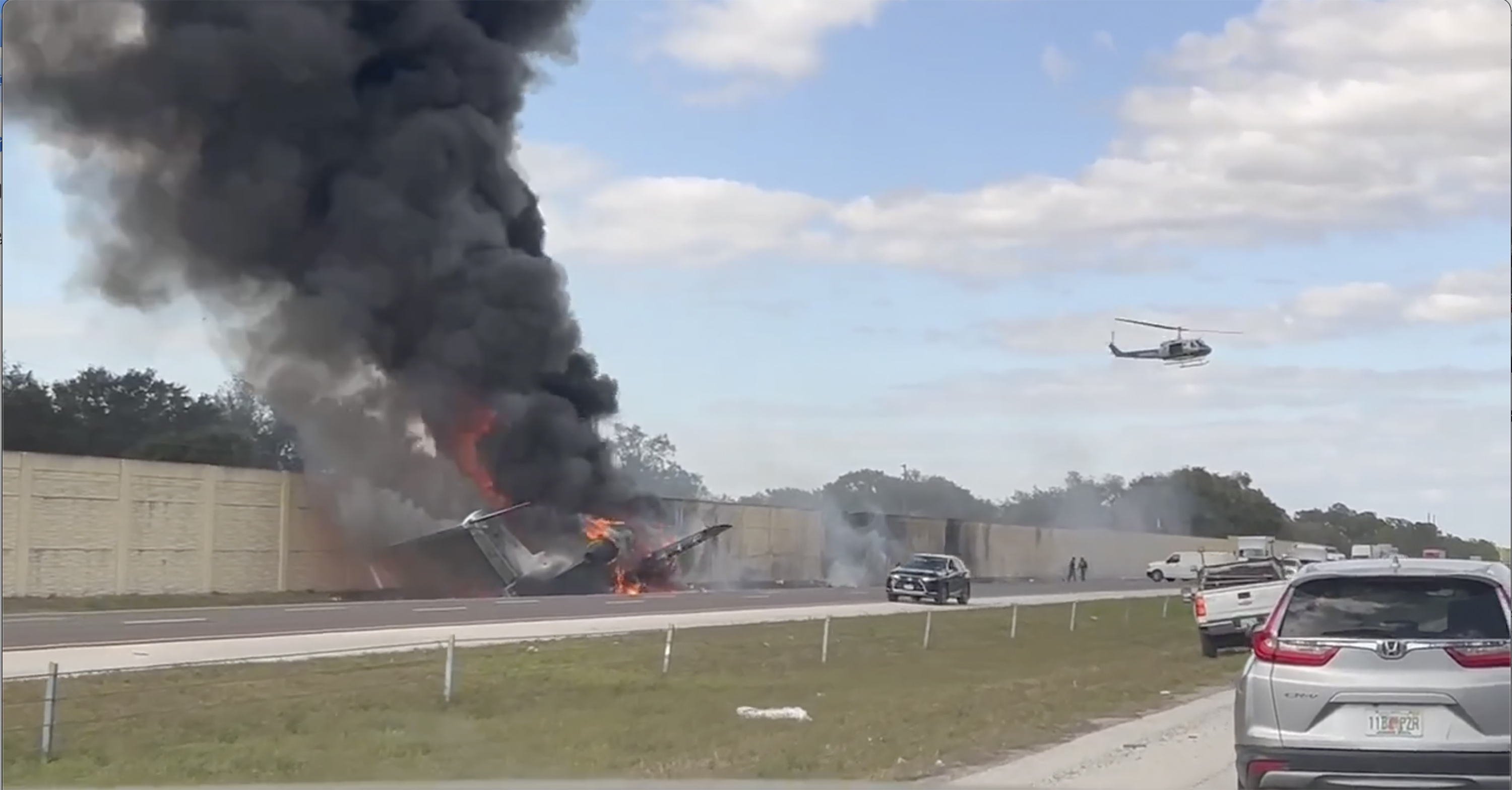 Smoke and fire fills the air after an airplane crashed on Interstate 75, Friday, Feb. 10, 2024 near Naples, Fla. Federal authorities have launched an investigation to determine why the private jet tried to make an emergency landing on the Florida interstate, colliding with a vehicle and sparking a fiery crash that left two people dead. (Chris O'Conner via AP)