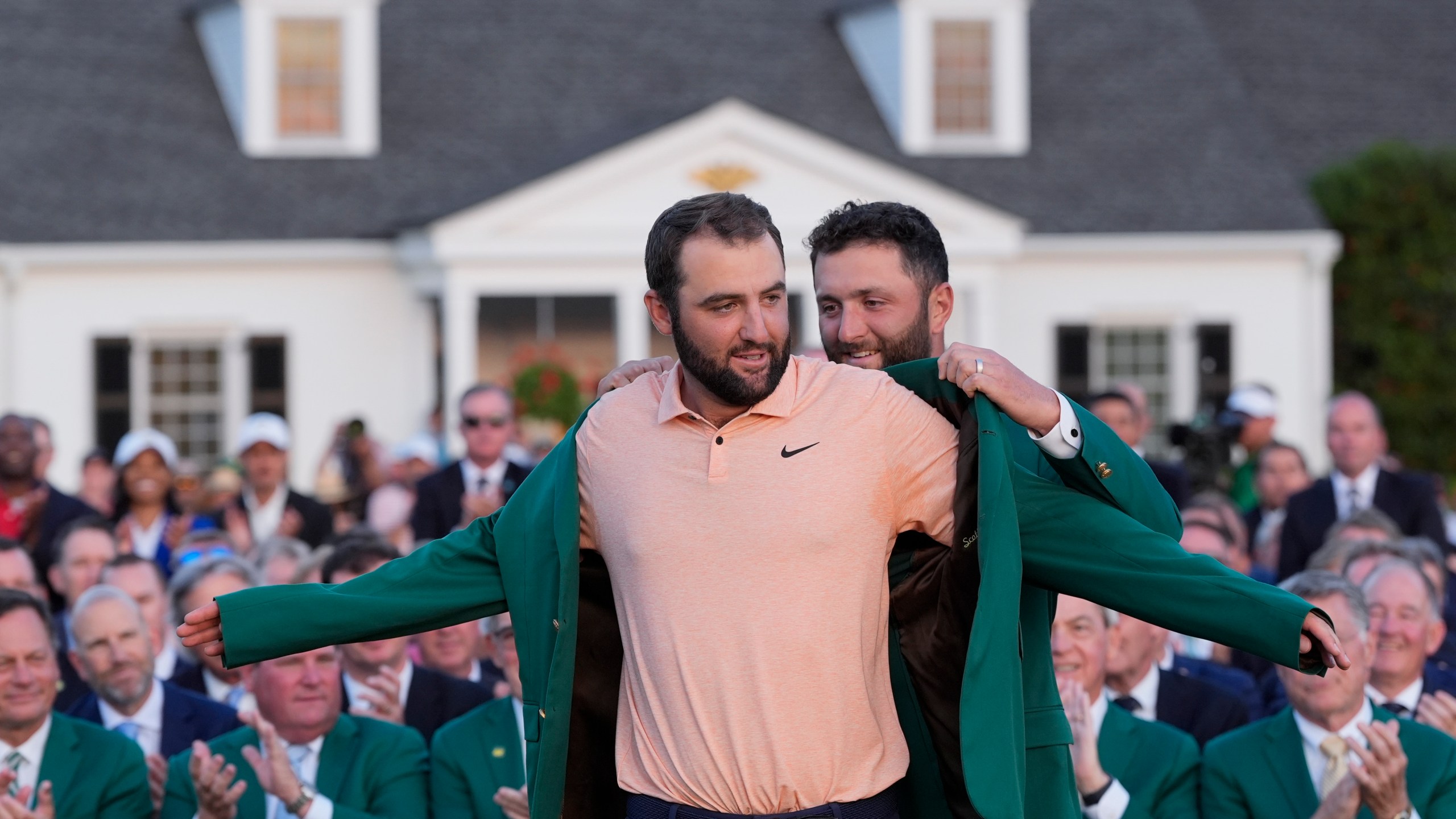 Jon Rahm, of Spain, puts the green jacket on winner Scottie Scheffler after the Masters golf tournament at Augusta National Golf Club Sunday, April 14, 2024, in Augusta, Ga. (AP Photo/David J. Phillip)