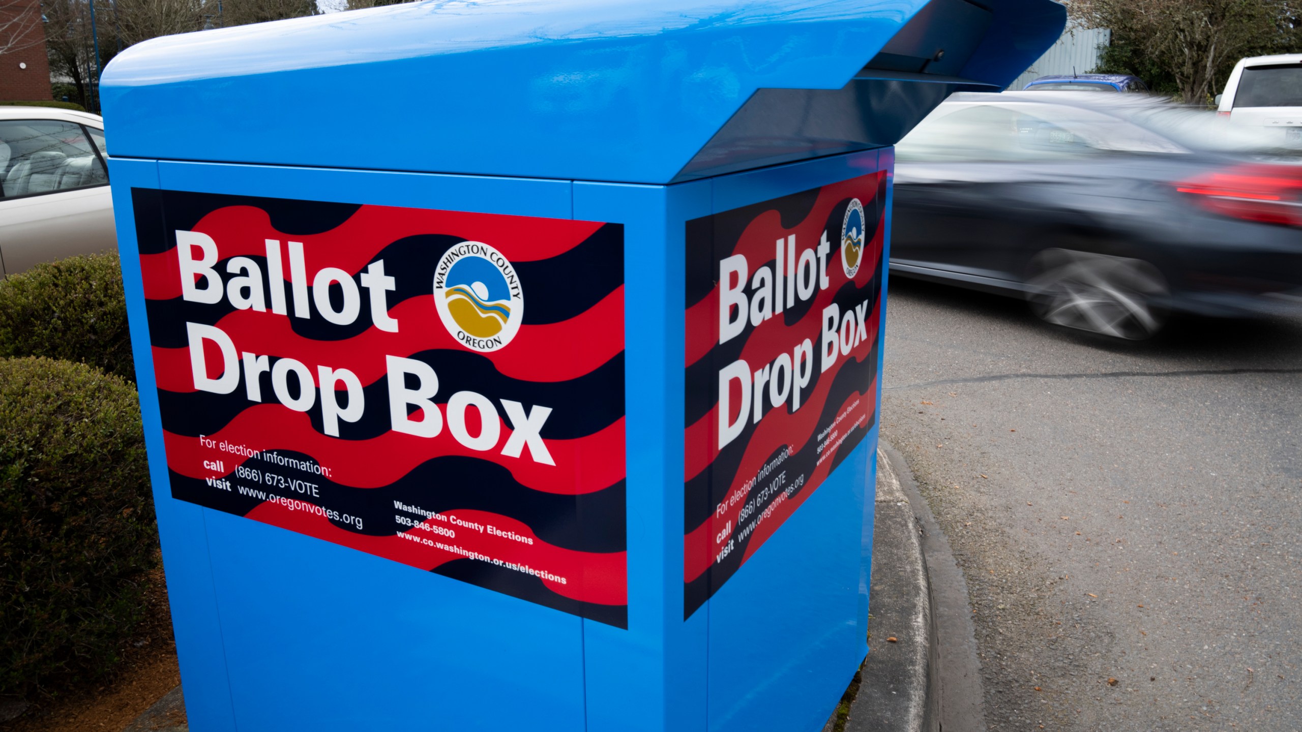 A car drives by a ballot drop box on Wednesday, March 6, 2024, in Sherwood, Ore. In Oregon's Multnomah County, home to Portland, the progressive district attorney who took office during the historical social justice movement of 2020 is being challenged by a more centrist candidate vowing to be tough on crime, highlighting the growing pressure on liberal prosecutors across the U.S. amid voter concerns over public drug use and disorder. (AP Photo/Jenny Kane)