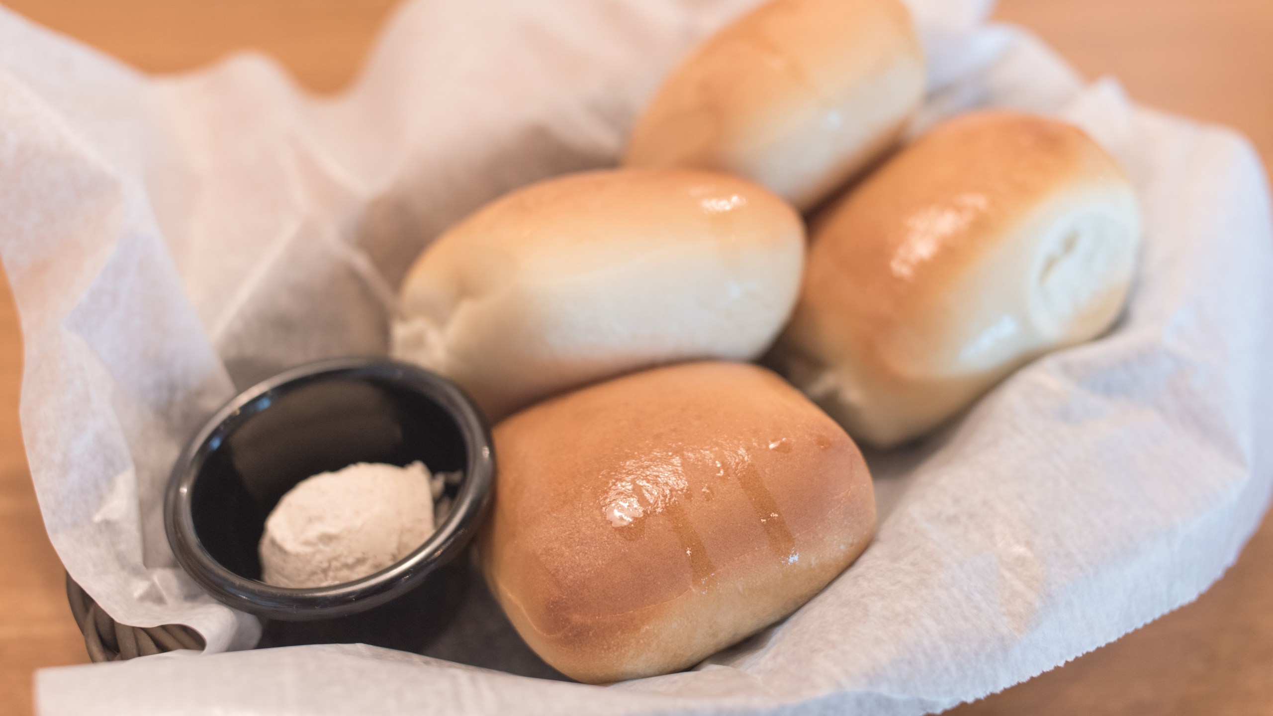 Texas Roadhouse Rolls with Cinnamon Honey Butter in a basket.;