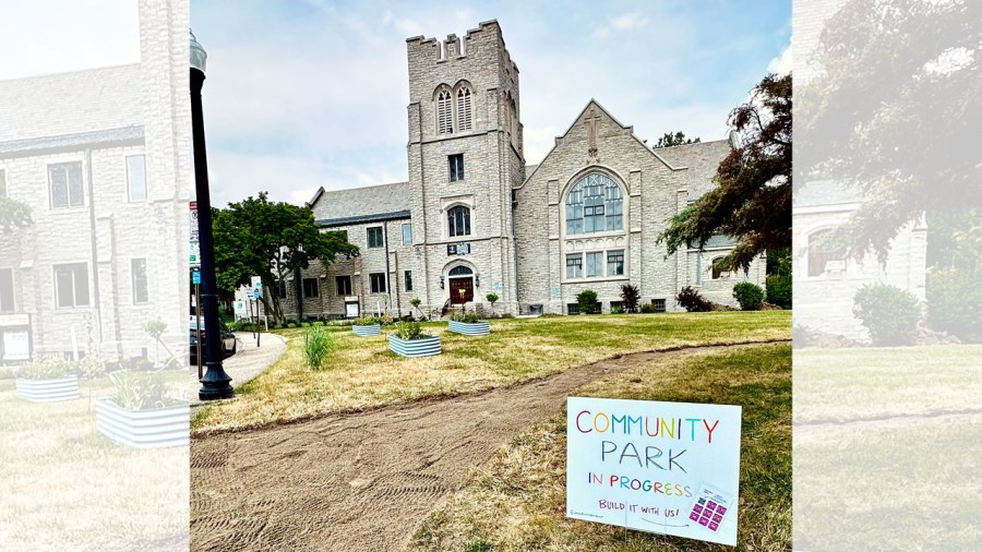A sign reads "Community Park in progress," sitting in the lawn of Indianola Presbyterian Park next to a path and lawn that are under light construction