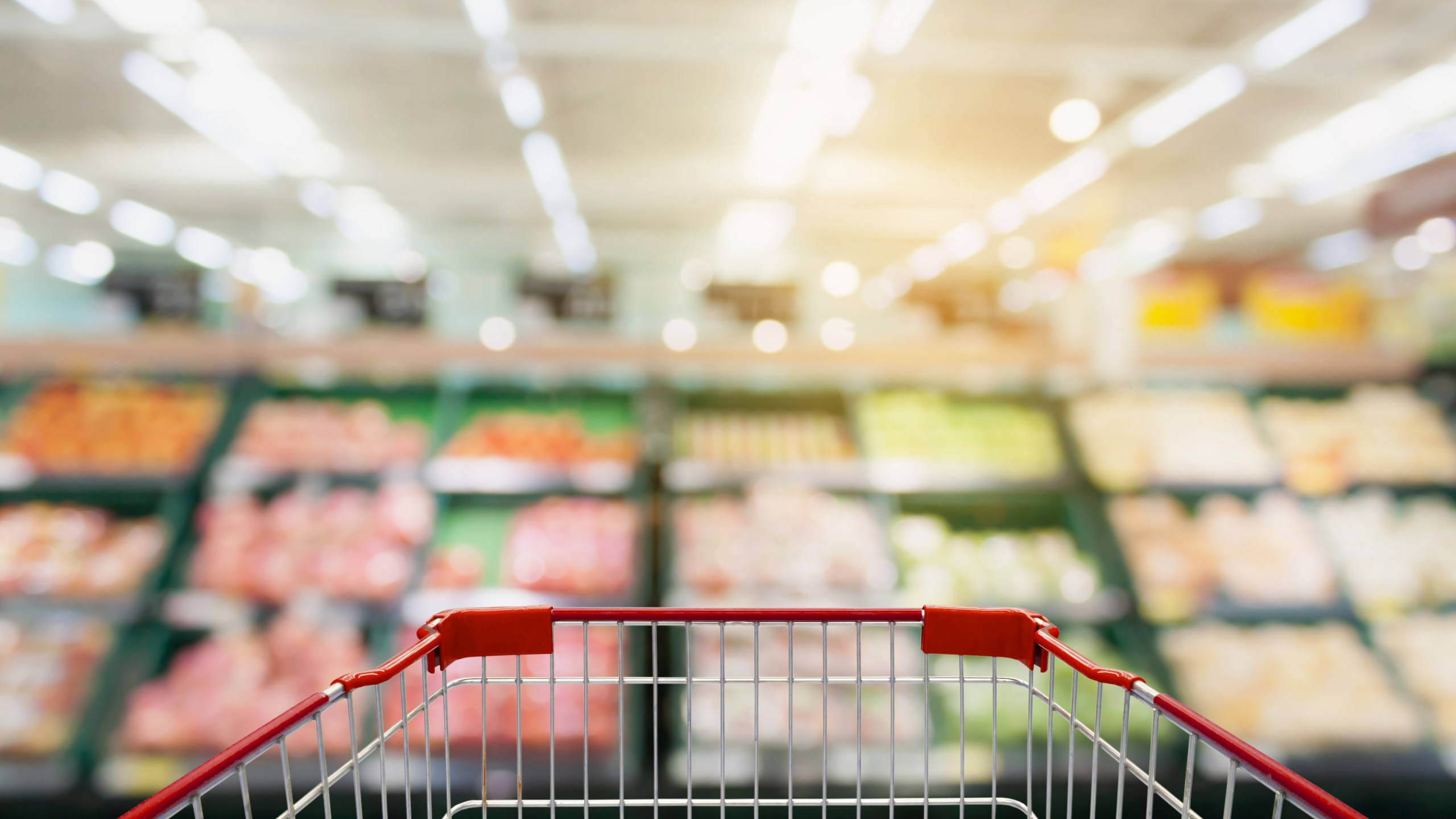 Shopping cart with Fruits and vegetables on shelves in supermarket blur background
