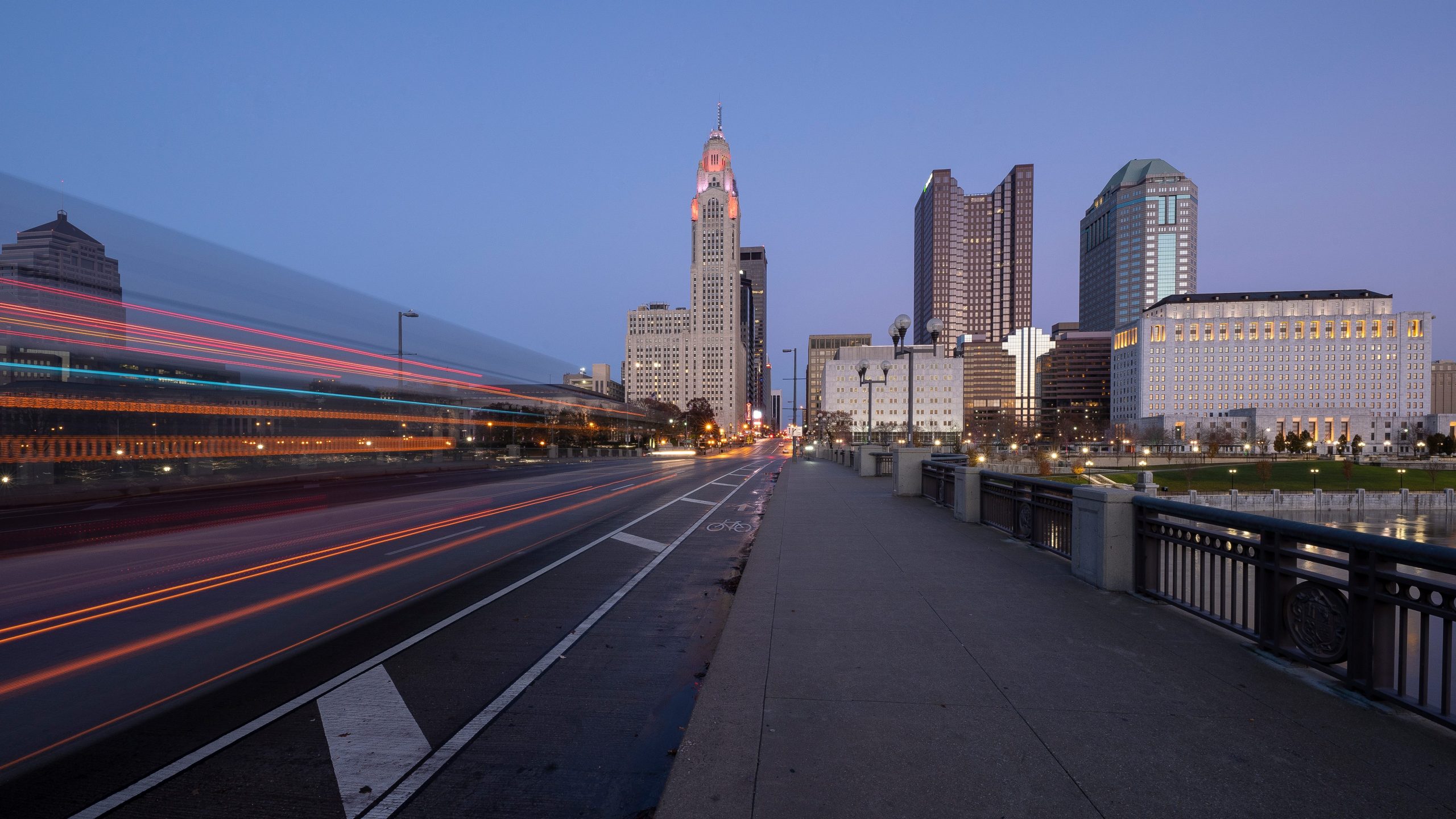 Evening Columbus Ohio skyline along the Scioto River at dusk with bus trails