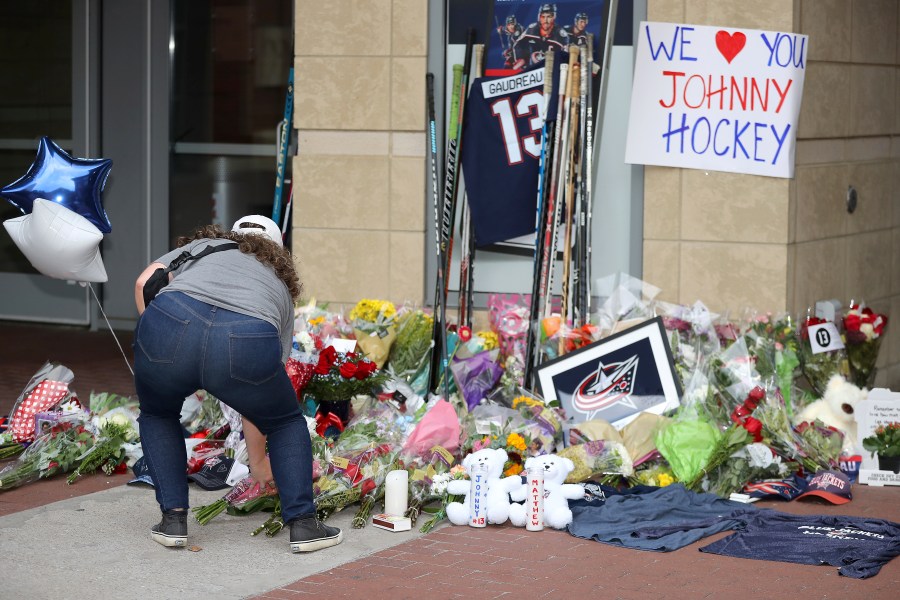 Kaitlin O'Hara of Columbus, places flowers at a memorial set up by fans for Blue Jackets hockey player Johnny Gaudreau in Columbus, Ohio, Aug. 30, 2024. Gaudreau, along with his brother Matthew, was fatally struck by a motorist while riding his bicycle on Thursday. (AP Photo/Joe Maiorana)