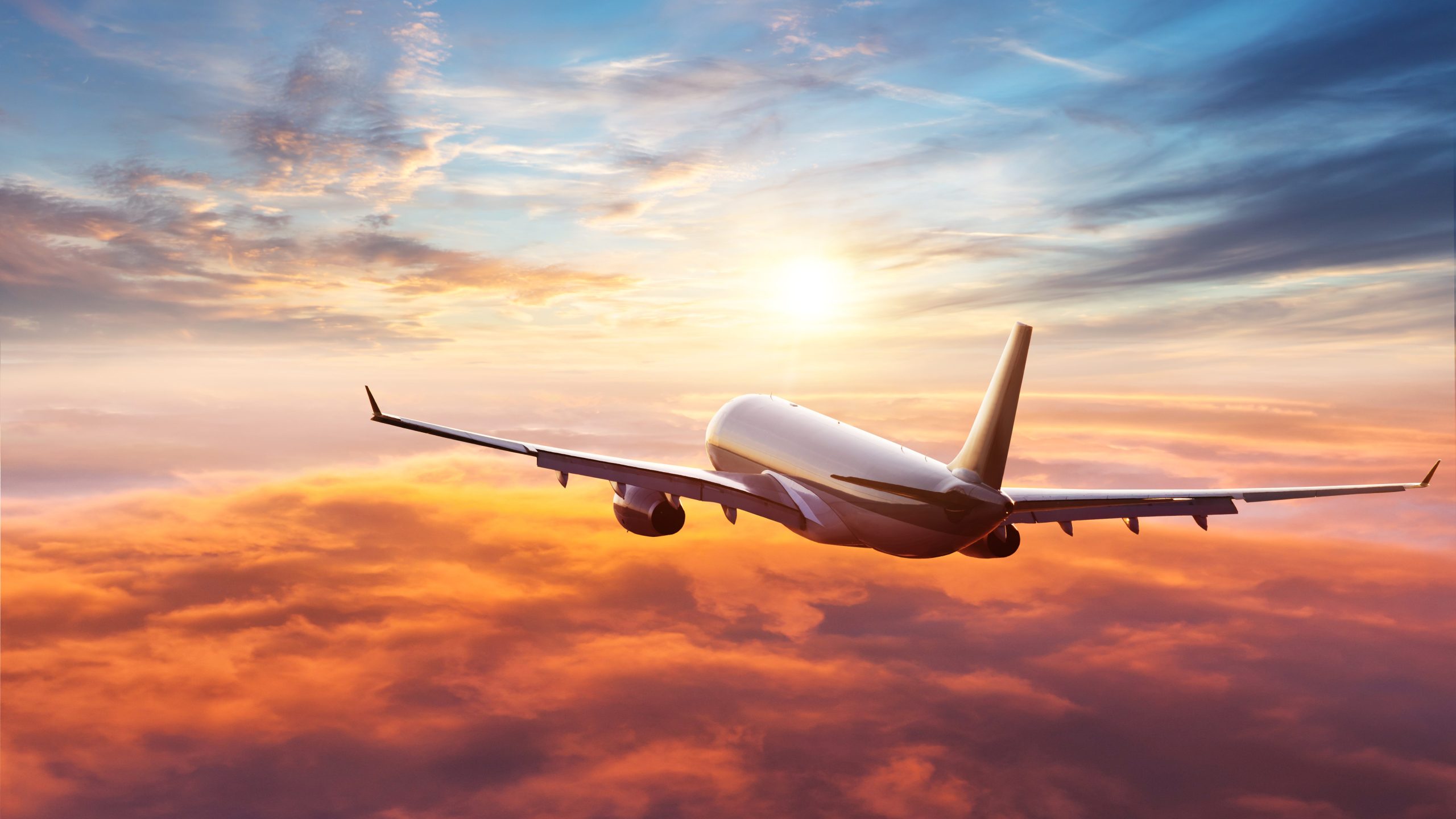 Passengers commercial airplane flying above clouds in sunset light. Concept of fast travel, holidays and business.