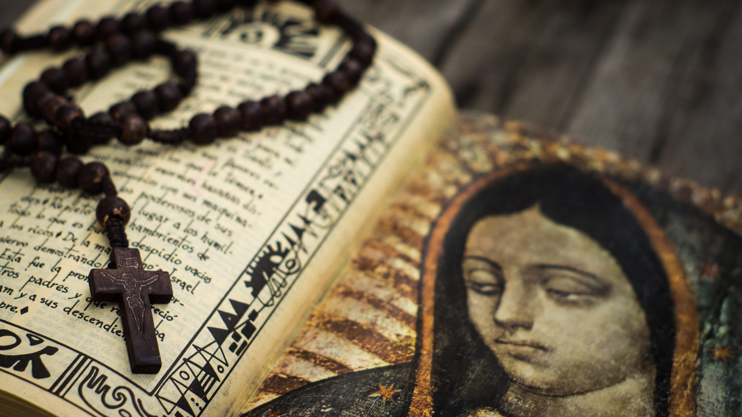 A Religious concept of a rosary and a bible on wood background