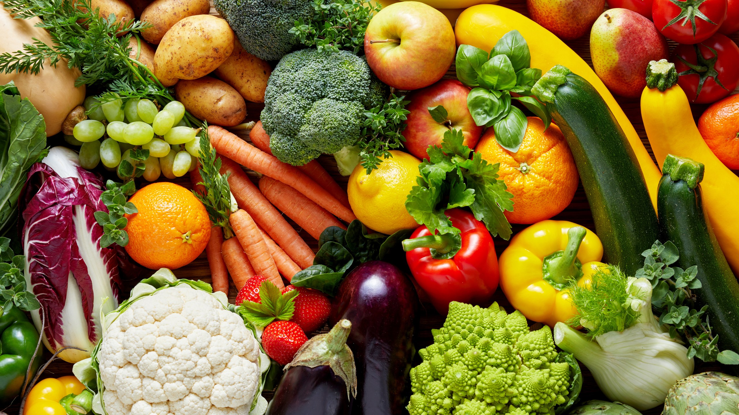 Different colorful fruits and vegetables all over the table in full frame studio shot (Adobe Stock)