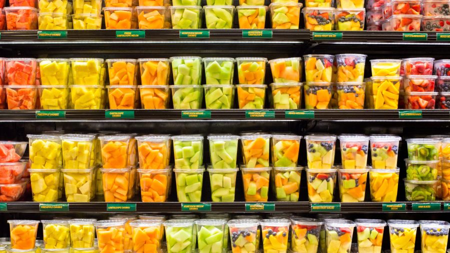 Assortment of fresh cut fruit in plastic containers in supermarket grocery display case