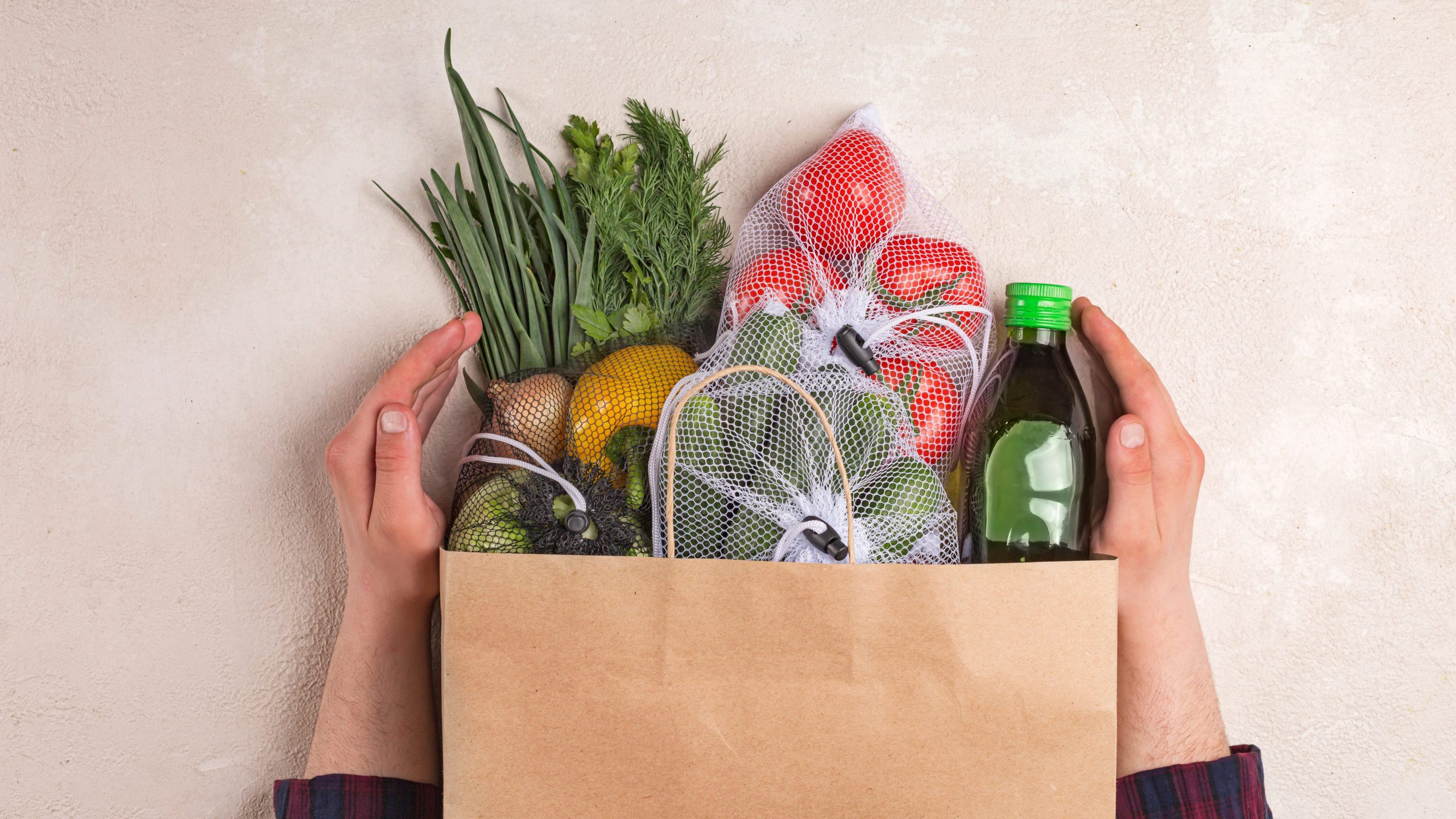 Man holds products in a paper bag. Vegetables in the range of shopping in the terrestrial and online store. top view