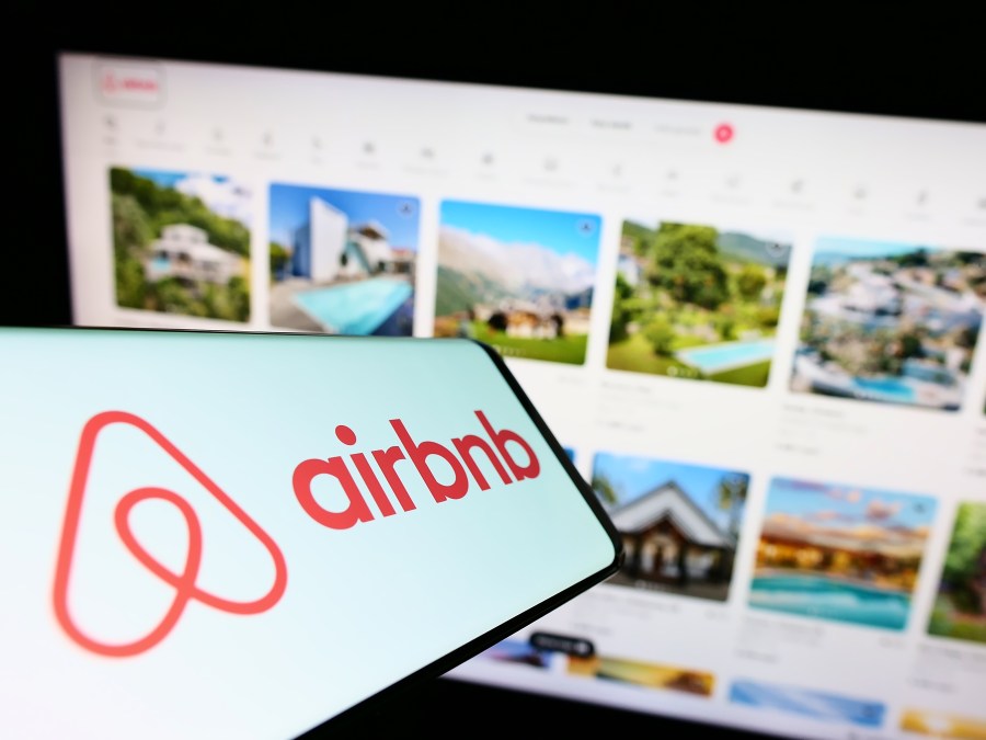 Smartphone with logo of American homestay marketplace company Airbnb Inc. on screen in front of business website. Focus on right of phone display.
