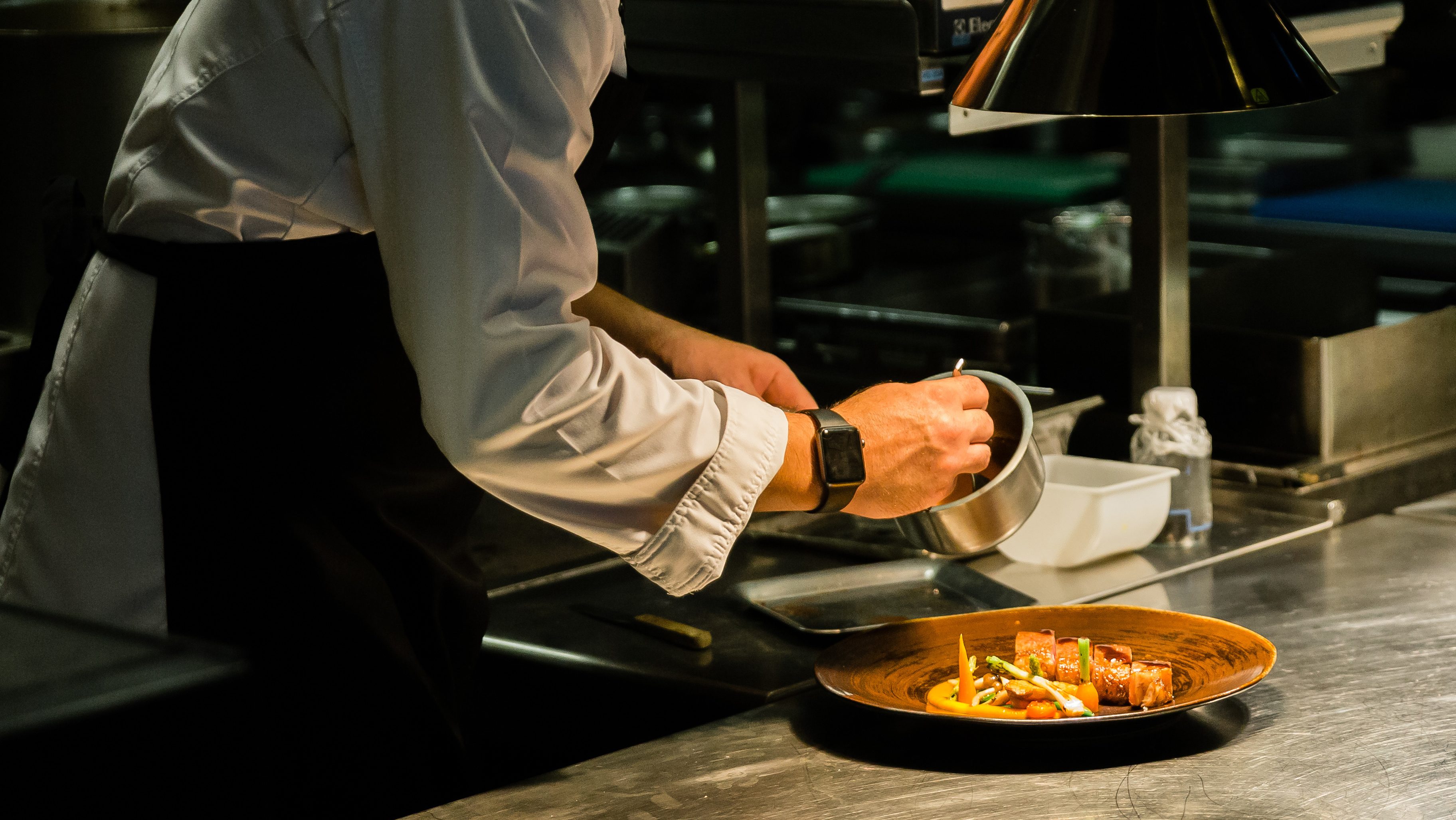Chef plating dish on kitchen counter while recording at kitchen hotel.