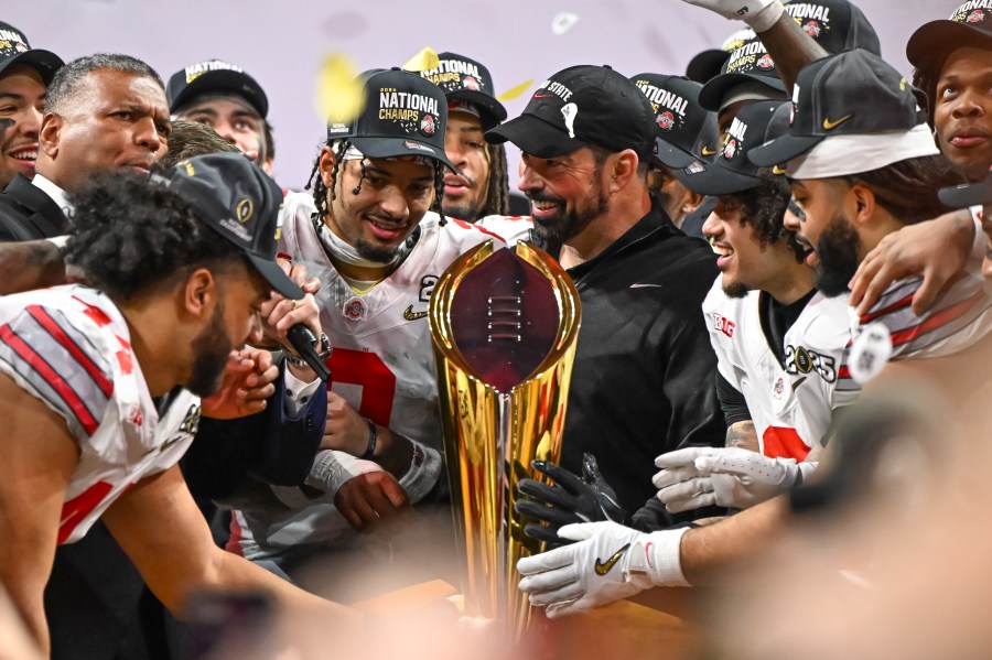 ATLANTA, GA - JANUARY 20: The Ohio State Buckeyes players along with Head Coach Ryan Day on the podium with National Championship trophy after the Ohio State Buckeyes versus Notre Dame Fighting Irish College Football Playoff National Championship game on January 20, 2025, at Mercedes-Benz Stadium in Atlanta, GA. (Photo by John Adams/Icon Sportswire via Getty Images)