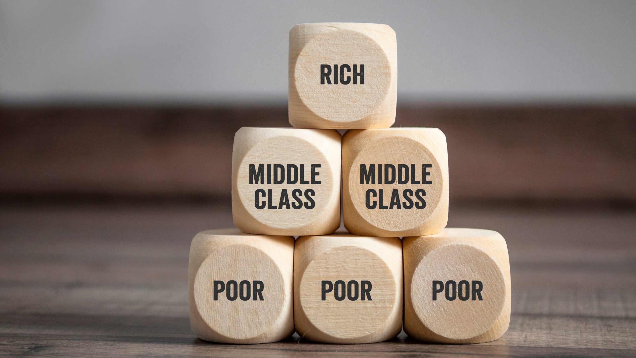 Pyramid made of cubes and dice with rich, middle class and poor on wooden background