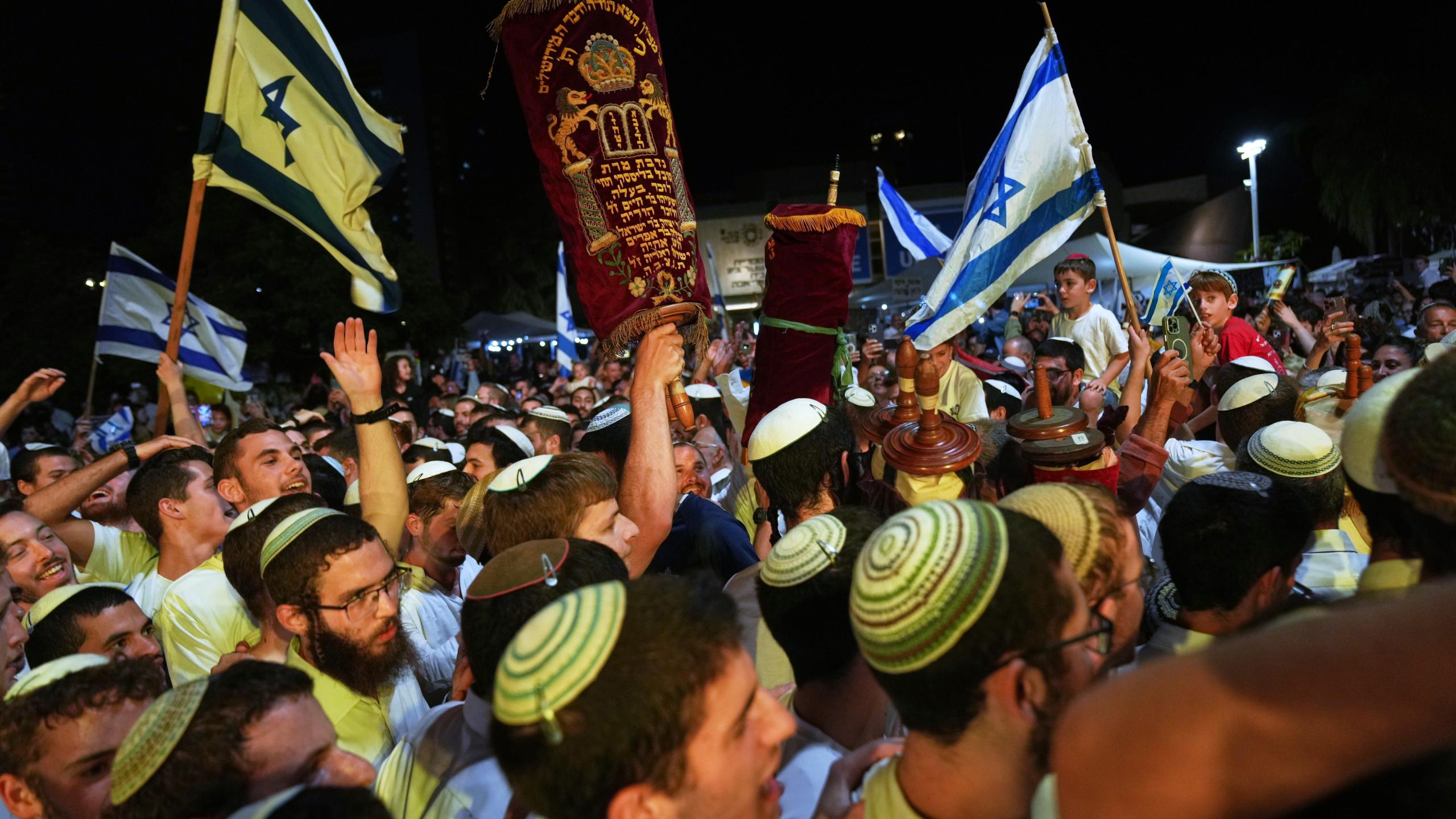 Jewish revelers dance and hold up the Torah as they celebrate the holiday of Simchat Torah at the plaza known as hostages square in Tel Aviv, Israel, Tuesday, Oct. 14, 2025. (AP Photo/Francisco Seco)