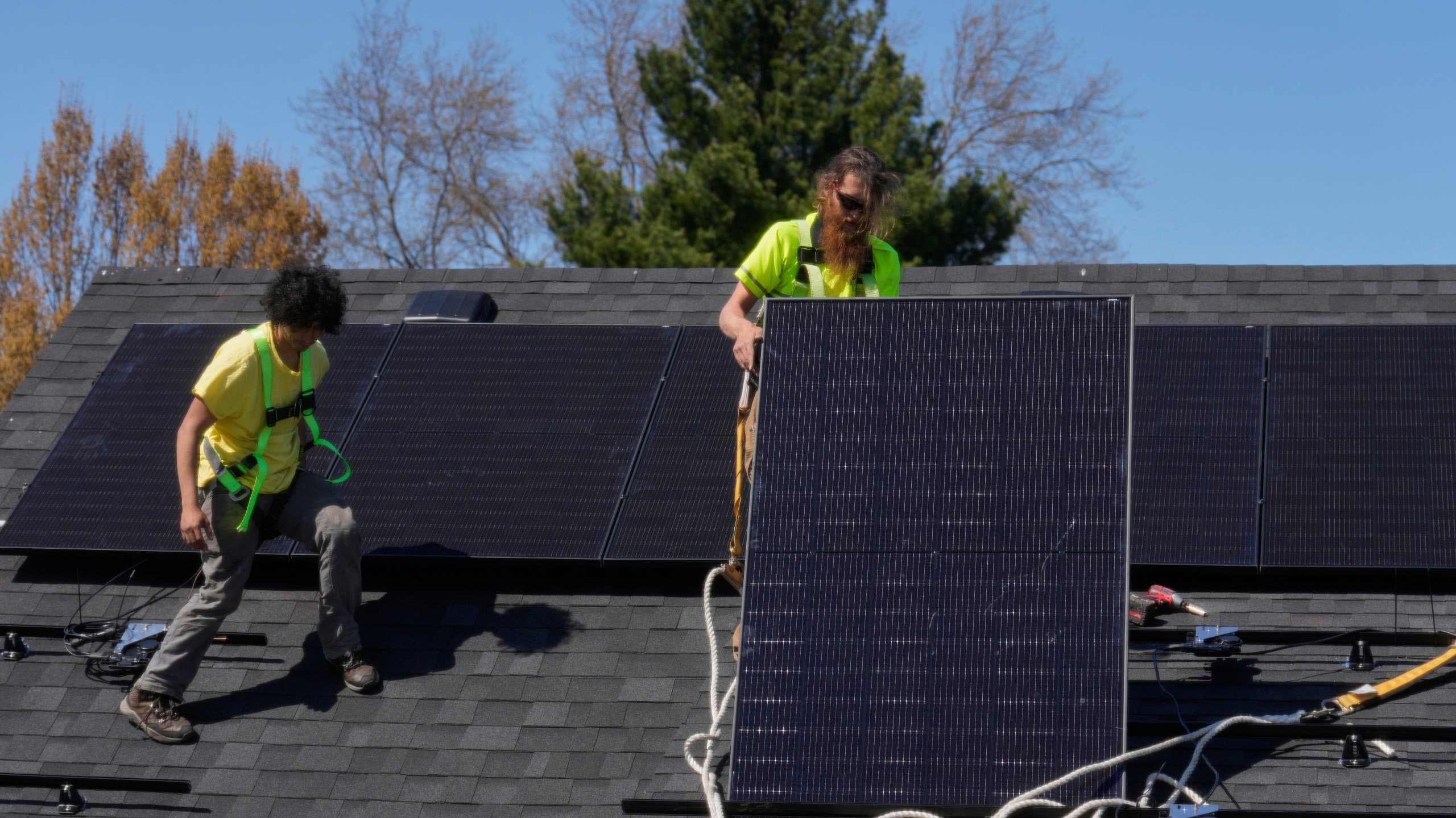 FILE - Brayan Santos, left, and Theodore Tanczuk, right, of solar installer YellowLite, put solar panels on the roof of a home in Lakewood, Ohio, April 16, 2025. (AP Photo/Sue Ogrocki, File)