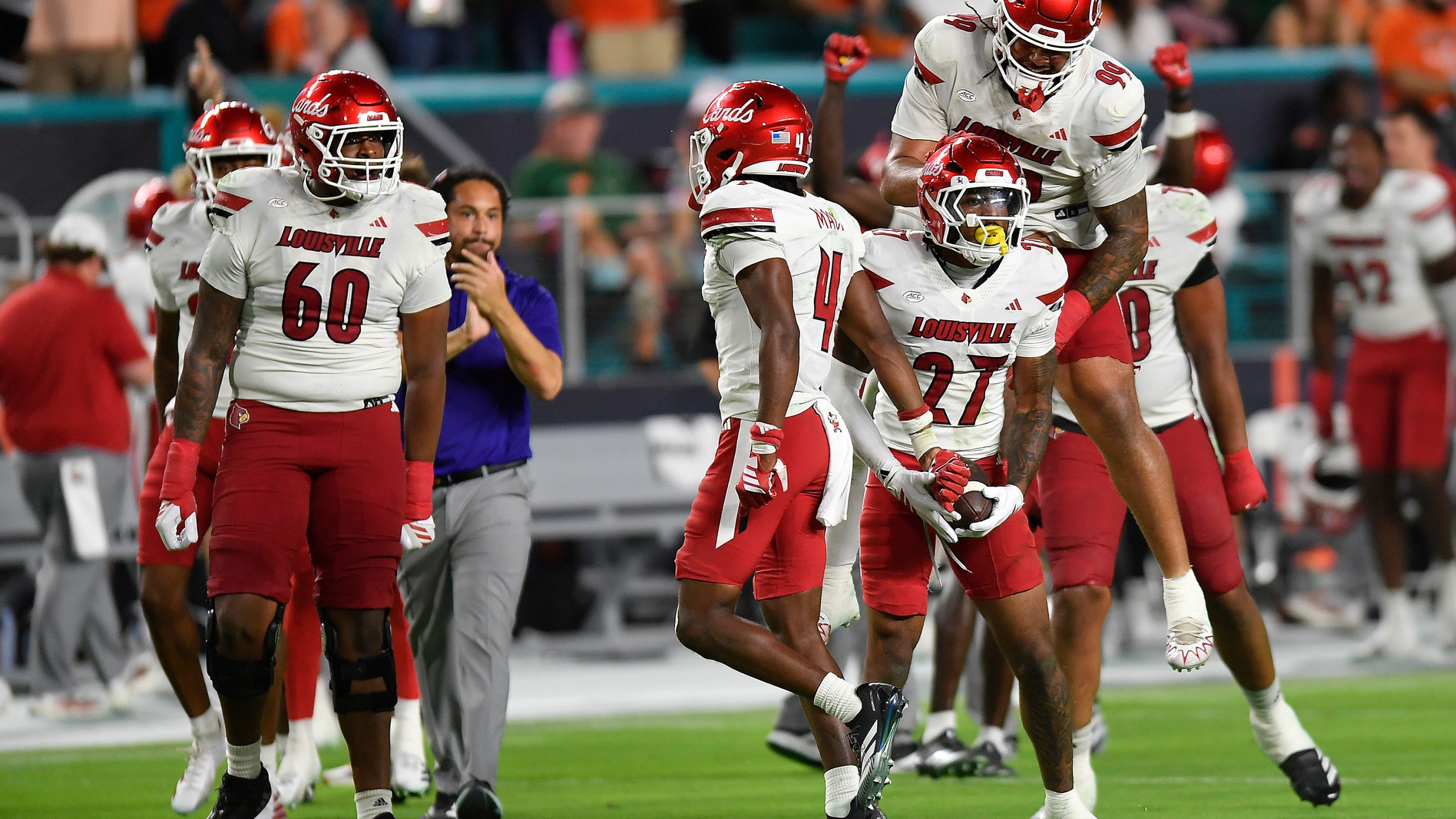 Louisville defensive back Jojo Evans Jr. (27) celebrates after intercepting a pass with defensive lineman Jordan Guerad (99) during the second half of an NCAA college football game against Miami, Friday, Oct. 17, 2025, in Miami Gardens, Fla. (AP Photo/Michael Laughlin)