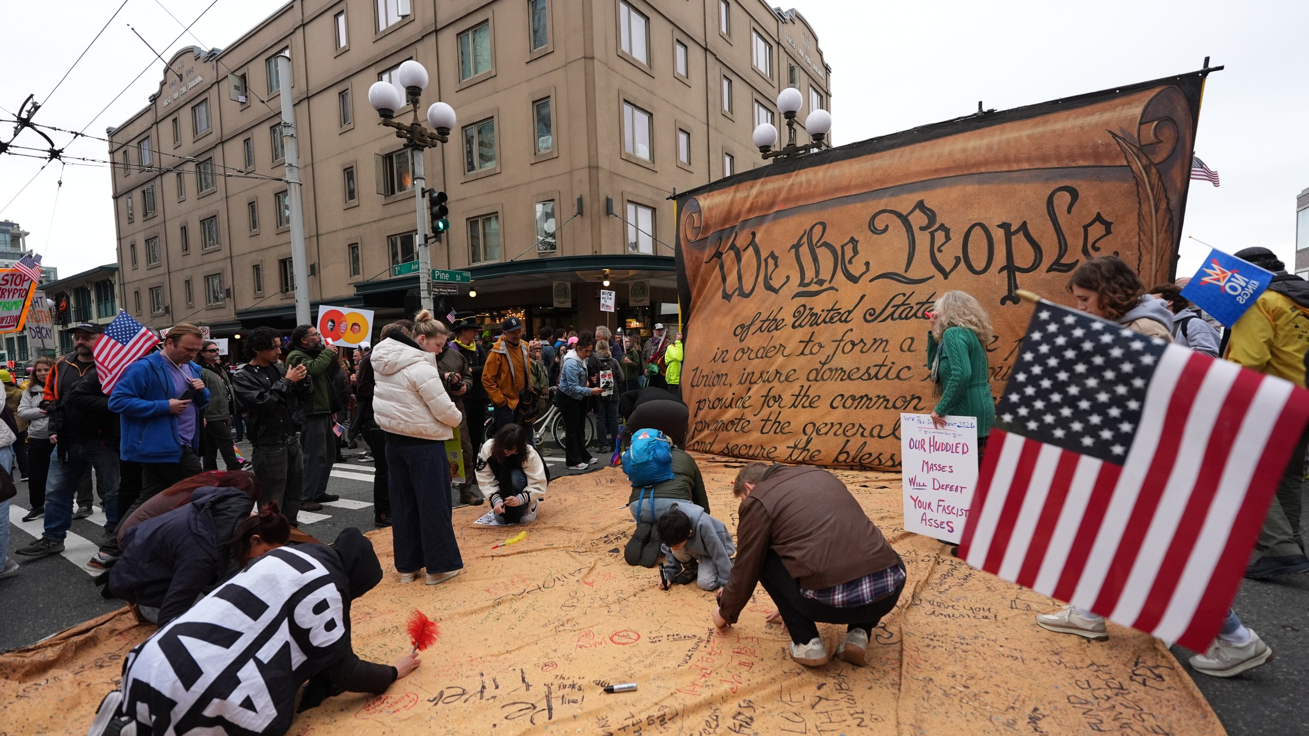 People are signing a giant Constitution as they take part in a "No Kings" protest Saturday, Oct. 18, 2025, in Seattle. (AP Photo/Lindsey Wasson)