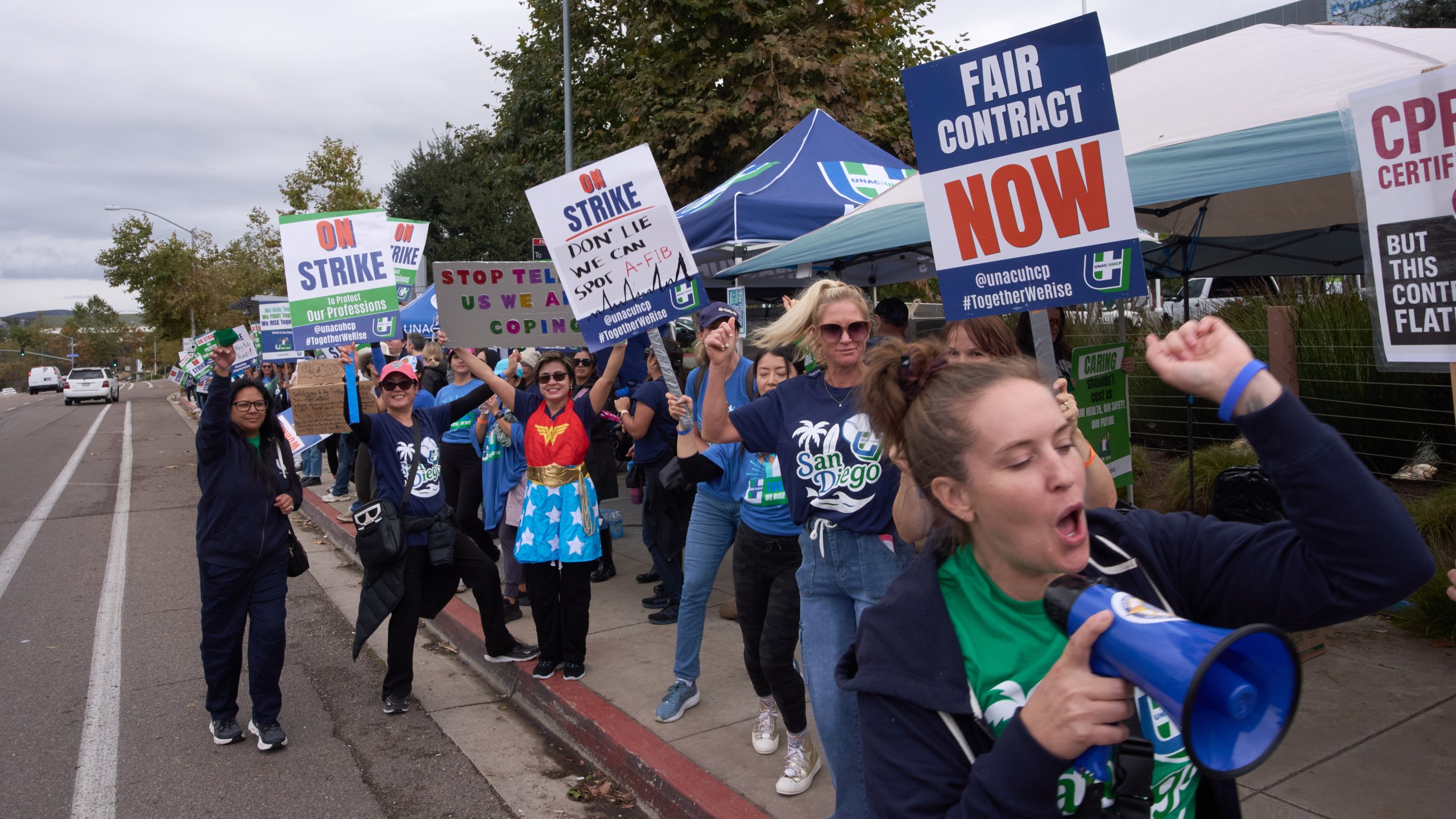 Kaiser Permanente health care workers hold signs and chant slogans while on strike in front of the Kaiser Permanente San Diego Medical Center Tuesday, Oct. 14, 2025, in San Diego. (AP Photo/Gregory Bull)