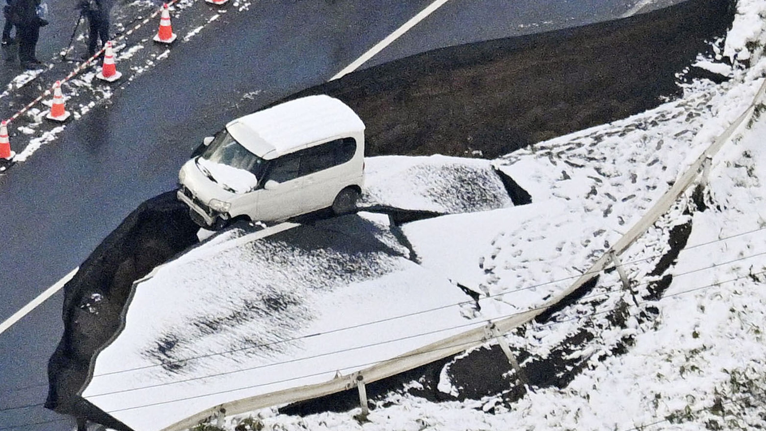 This aerial photo shows a vehicle sitting on a damaged road in Tohoku town, Aomori prefecture, northern Japan Tuesday, Dec. 9, 2025, following a powerful earthquake on late Monday. (Kyodo News via AP)