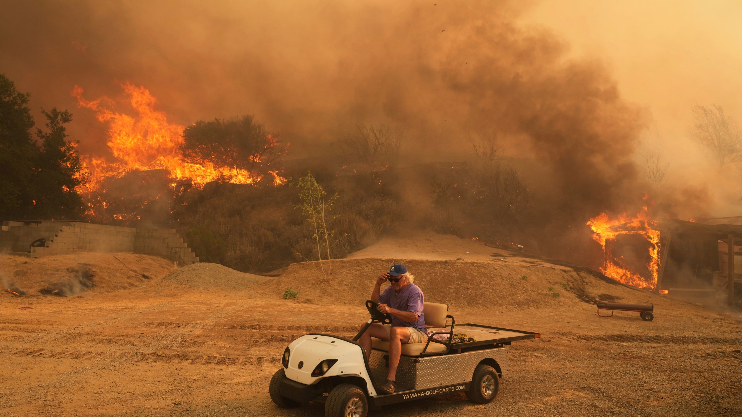 FILE - A resident rides a golf cart as he exits his property while the Canyon Fire burns on Aug. 7, 2025, in Hasley Canyon, Calif. (AP Photo/Marcio Jose Sanchez, File)