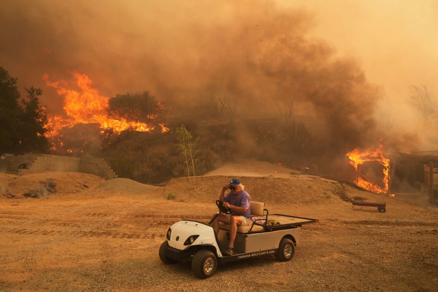 FILE - A resident rides a golf cart as he exits his property while the Canyon Fire burns on Aug. 7, 2025, in Hasley Canyon, Calif. (AP Photo/Marcio Jose Sanchez, File)