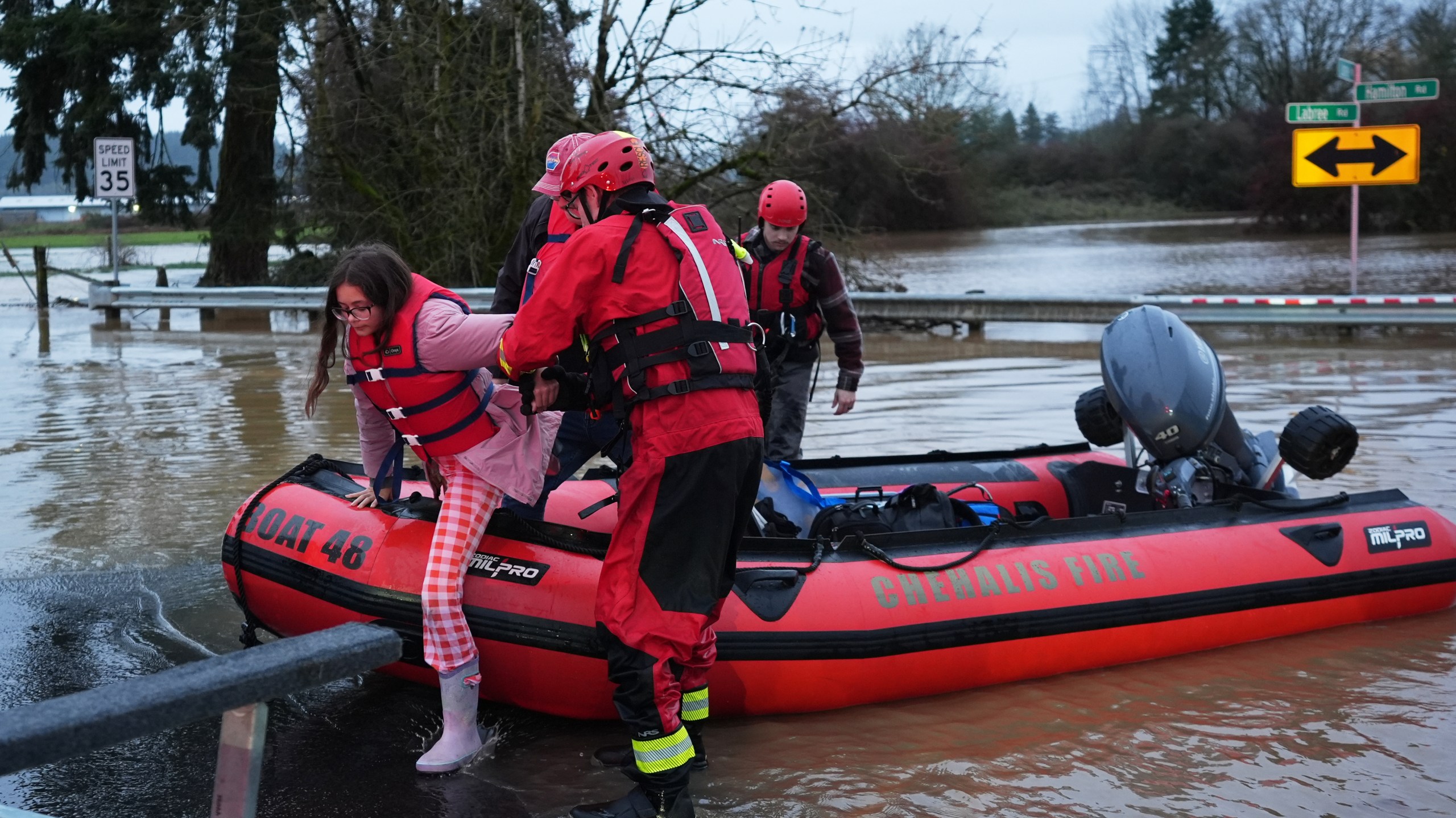Maery Schine, 11, is helped out of a rescue boat by rescue workers with Chehalis Fire after evacuating with her father Patric, second from left, following flooding after heavy rains in the region Tuesday, Dec. 9, 2025, in Chehalis, Wash. (AP Photo/Lindsey Wasson)