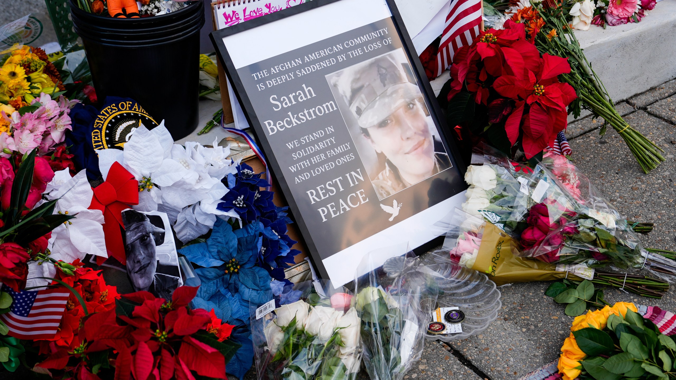 Flowers, challenge coins and other items lay near a photograph of U.S. Army Spc. Sarah Beckstrom at a makeshift memorial outside of Farragut West Station, near the site where two National Guard members were shot, Monday, Dec. 1, 2025, in Washington. (AP Photo/Julia Demaree Nikhinson)