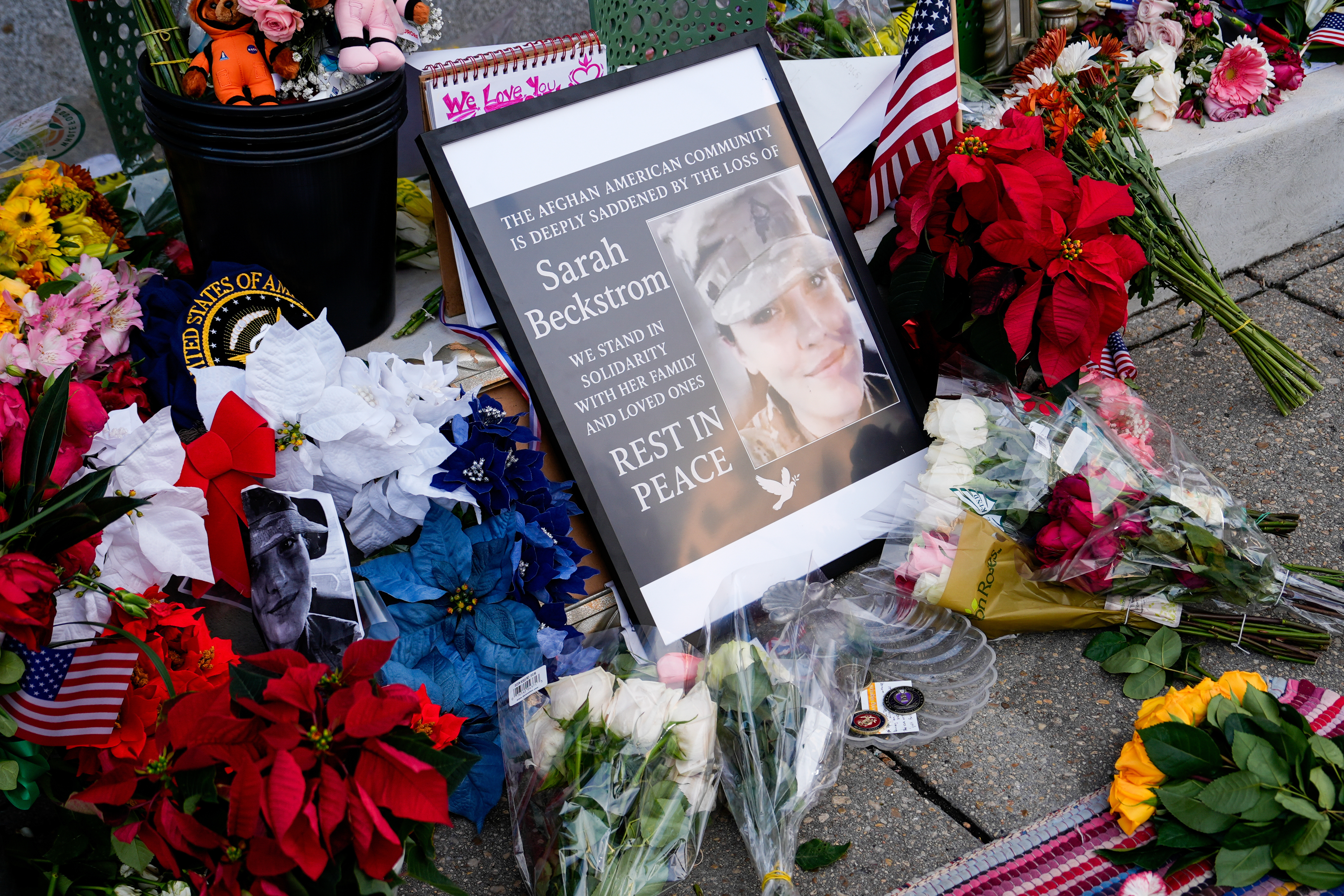 Flowers, challenge coins and other items lay near a photograph of U.S. Army Spc. Sarah Beckstrom at a makeshift memorial outside of Farragut West Station, near the site where two National Guard members were shot, Monday, Dec. 1, 2025, in Washington. (AP Photo/Julia Demaree Nikhinson)