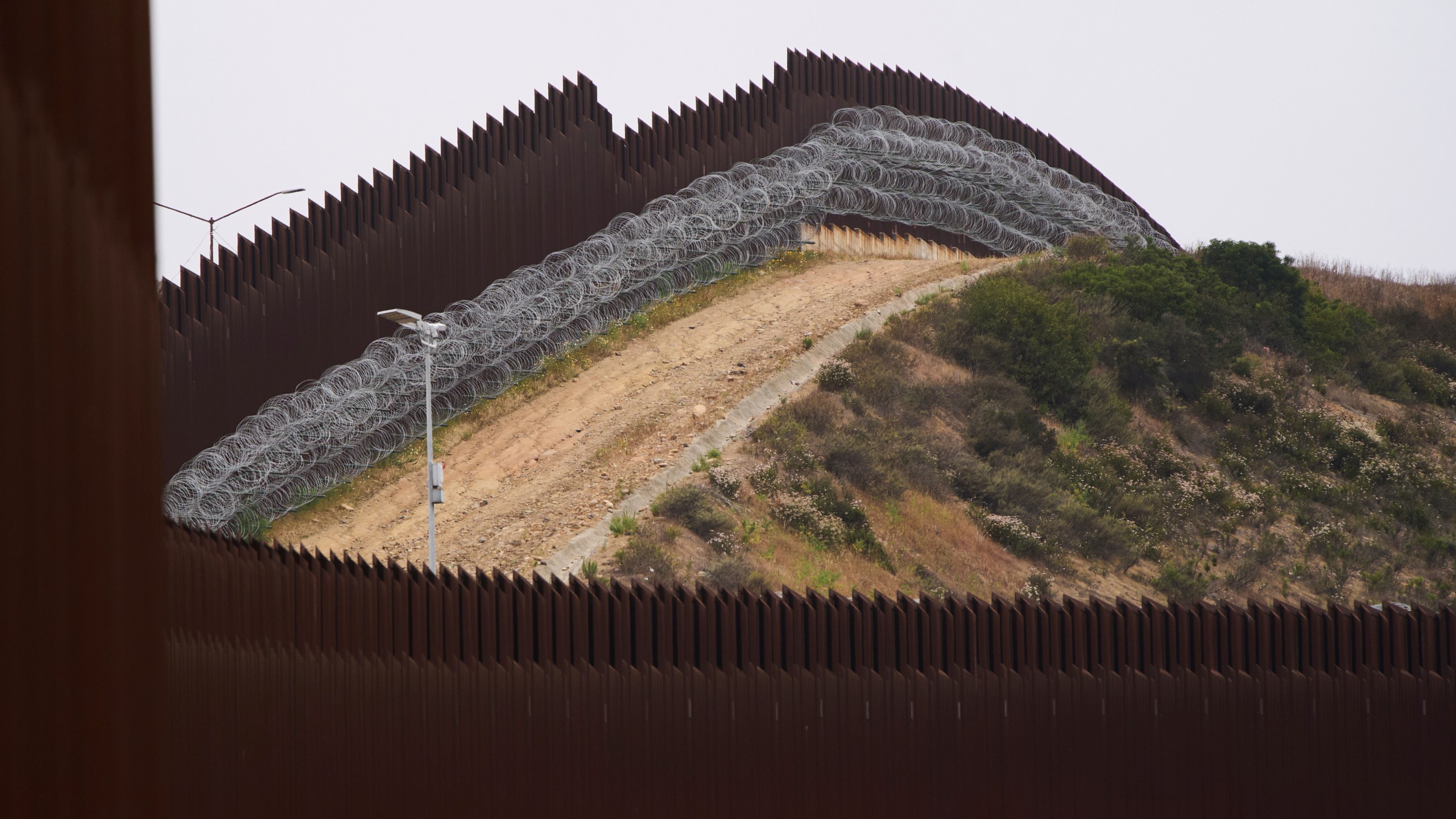 FILE - Concertina wire lines the interior of a border wall separating Tijuana, Mexico, from the United States, June 4, 2025, in San Diego. (AP Photo/Gregory Bull, File)