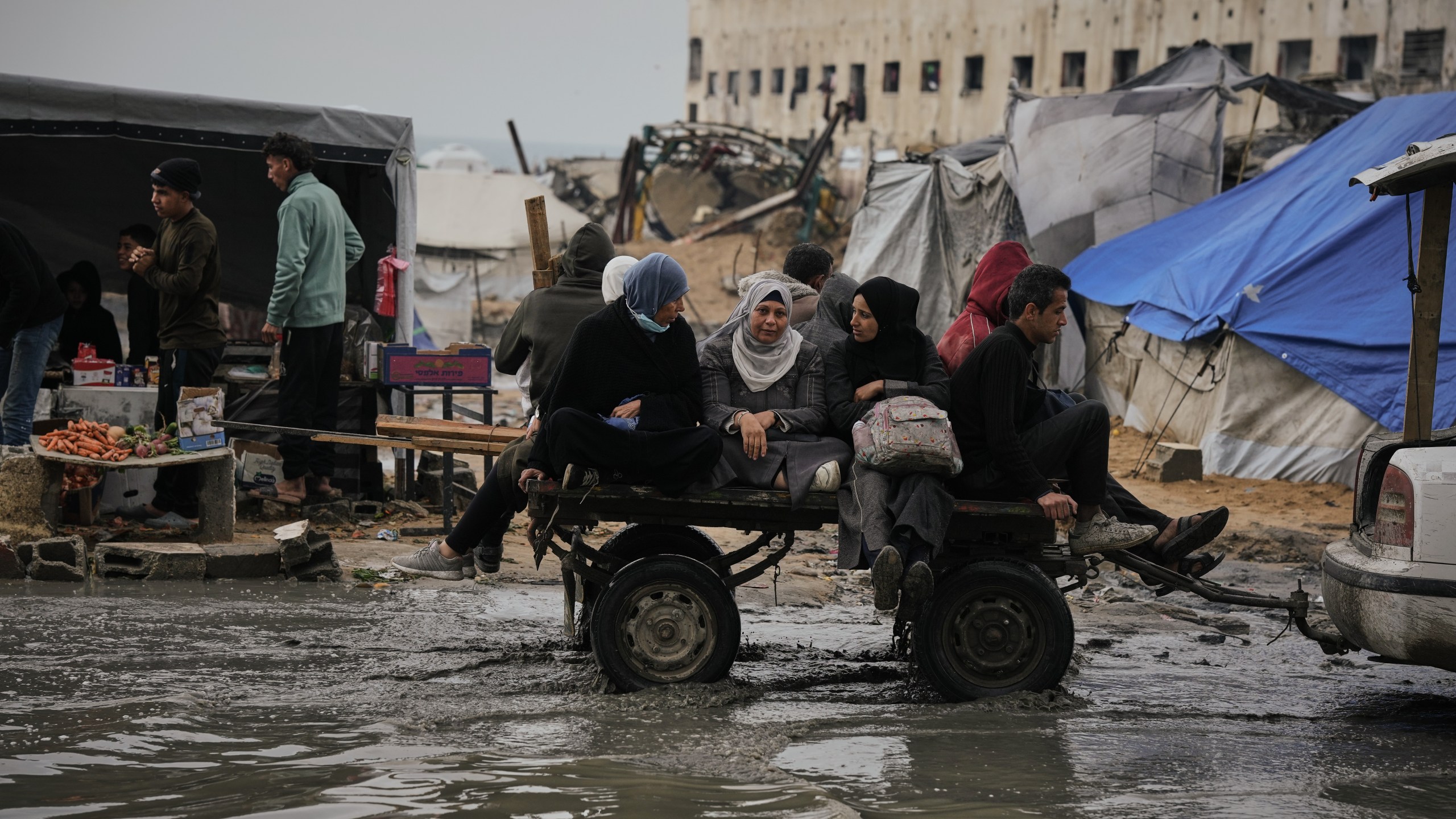 Palestinians ride in a cart pulled by a vehicle through a flooded street after stormy weather in Gaza City Wednesday, Dec. 10, 2025. (AP Photo/Jehad Alshrafi)