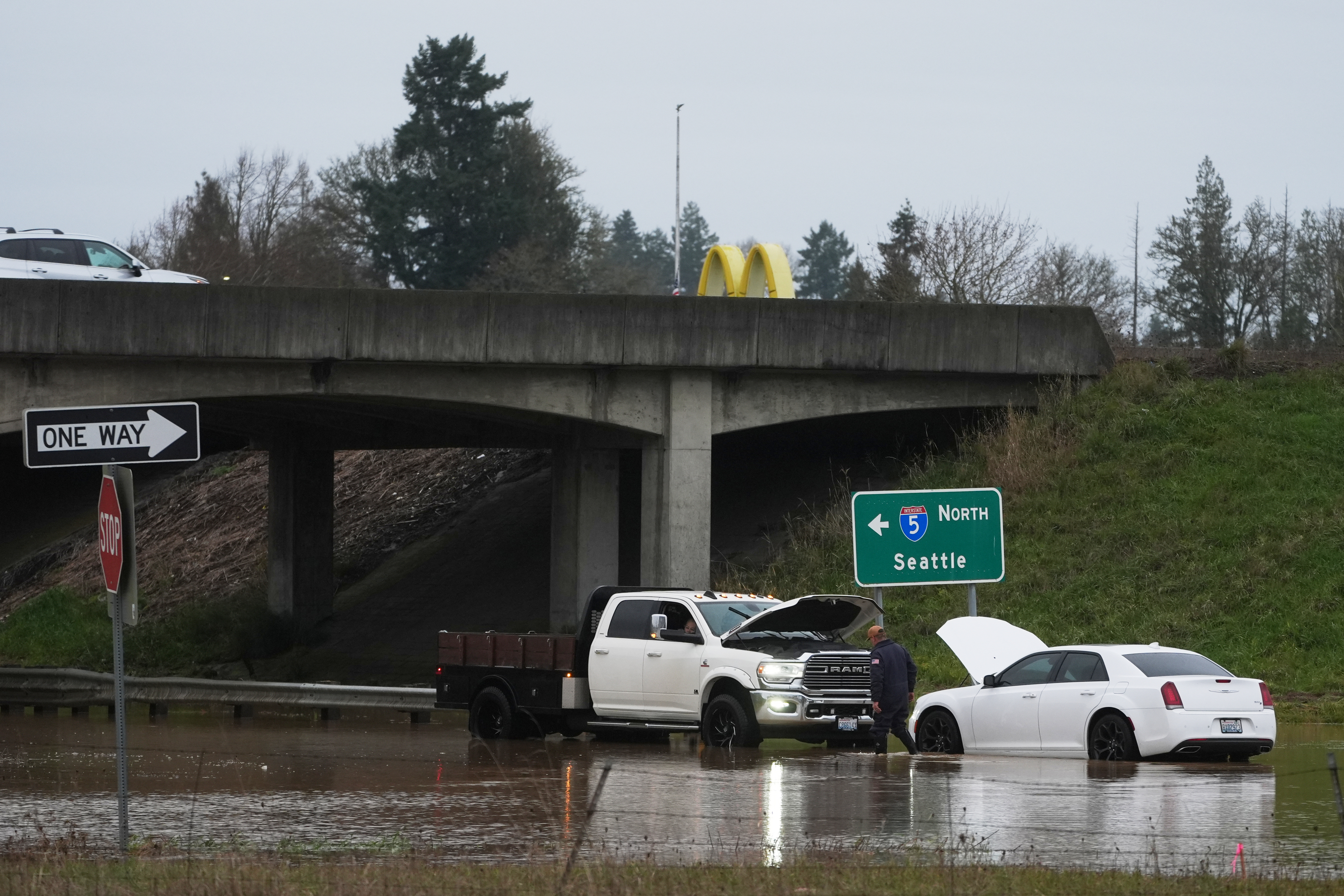 A man checks on a car caught in flooding after heavy rains Tuesday, Dec. 9, 2025, in Napavine, Wash. (AP Photo/Lindsey Wasson)
