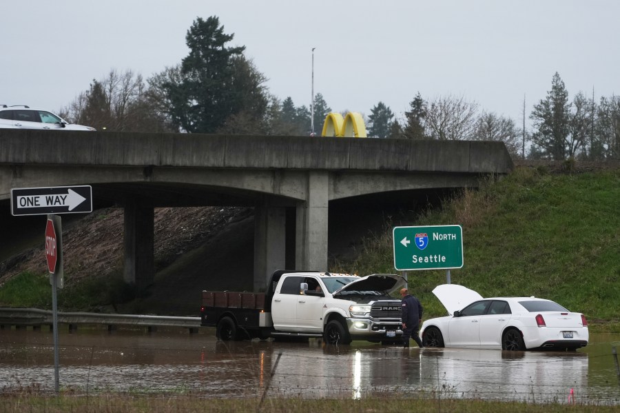 A man checks on a car caught in flooding after heavy rains Tuesday, Dec. 9, 2025, in Napavine, Wash. (AP Photo/Lindsey Wasson)
