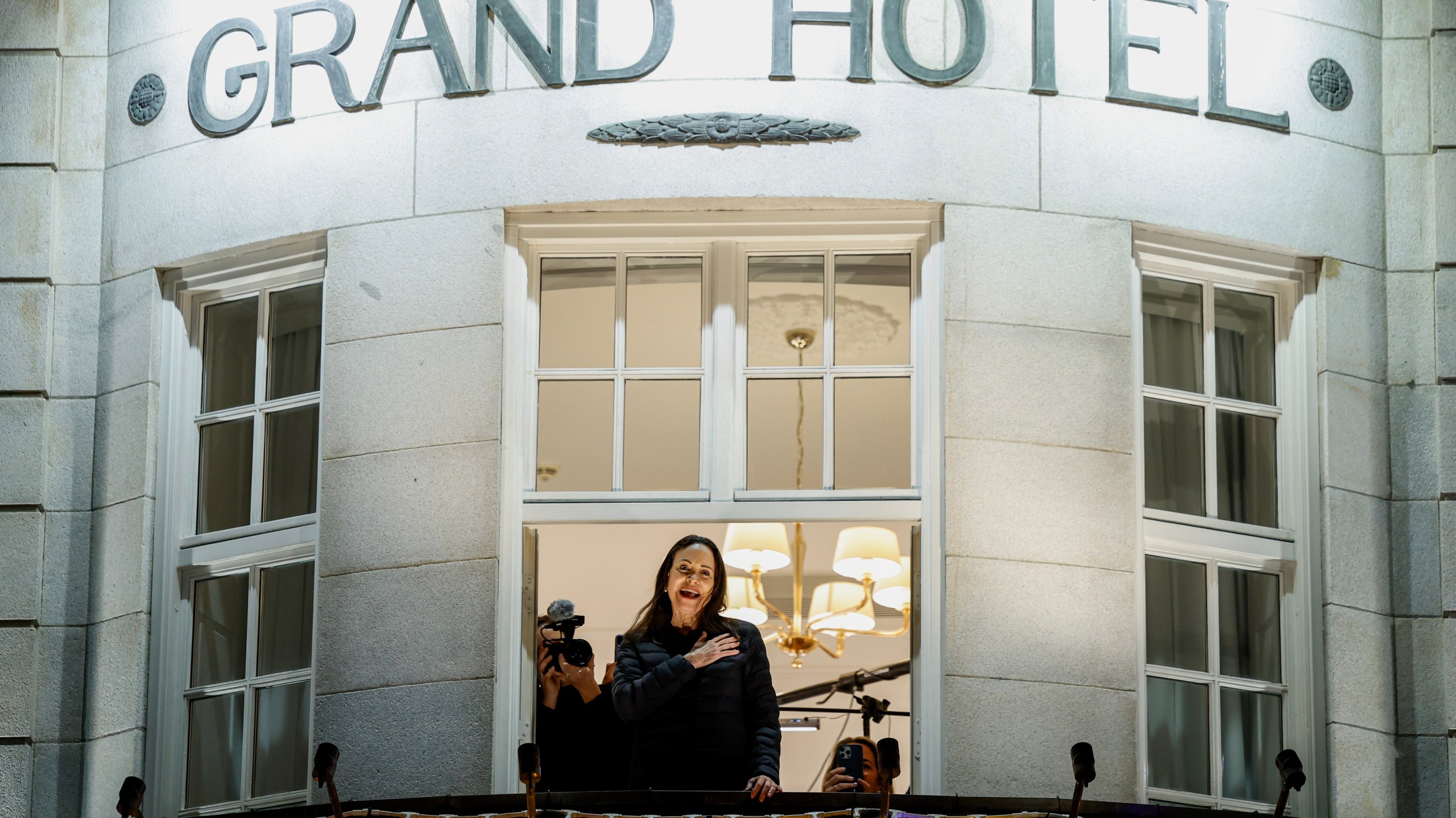 Nobel Peace Prize laureate Maria Corina Machado reacts to the crowd gathered below from a balcony at the Grand Hotel, in Oslo, Norway, early Thursday, Dec. 11, 2025. (Jonas Been Henriksen/NTB Scanpix via AP)