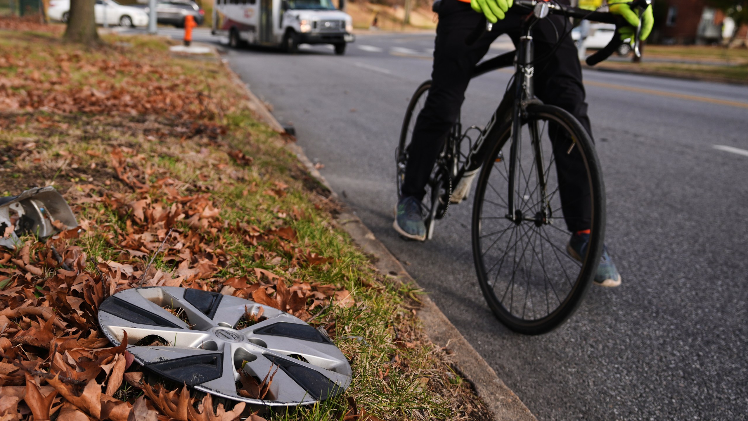 Cyclist Barnaby Wickham steps down and dismounts his bike after spotting a lost hubcap on the side of the road, Thursday, Dec. 11, 2025, in Baltimore. (AP Photo/Stephanie Scarbrough)